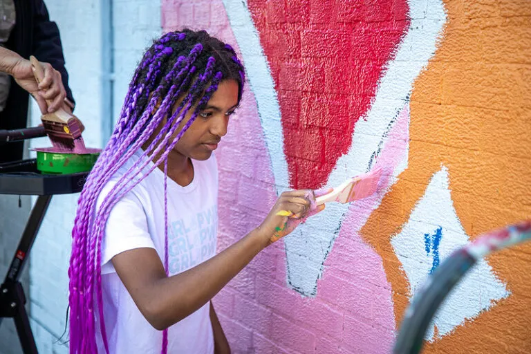student adds pink paint to Mural for Willard Elementary